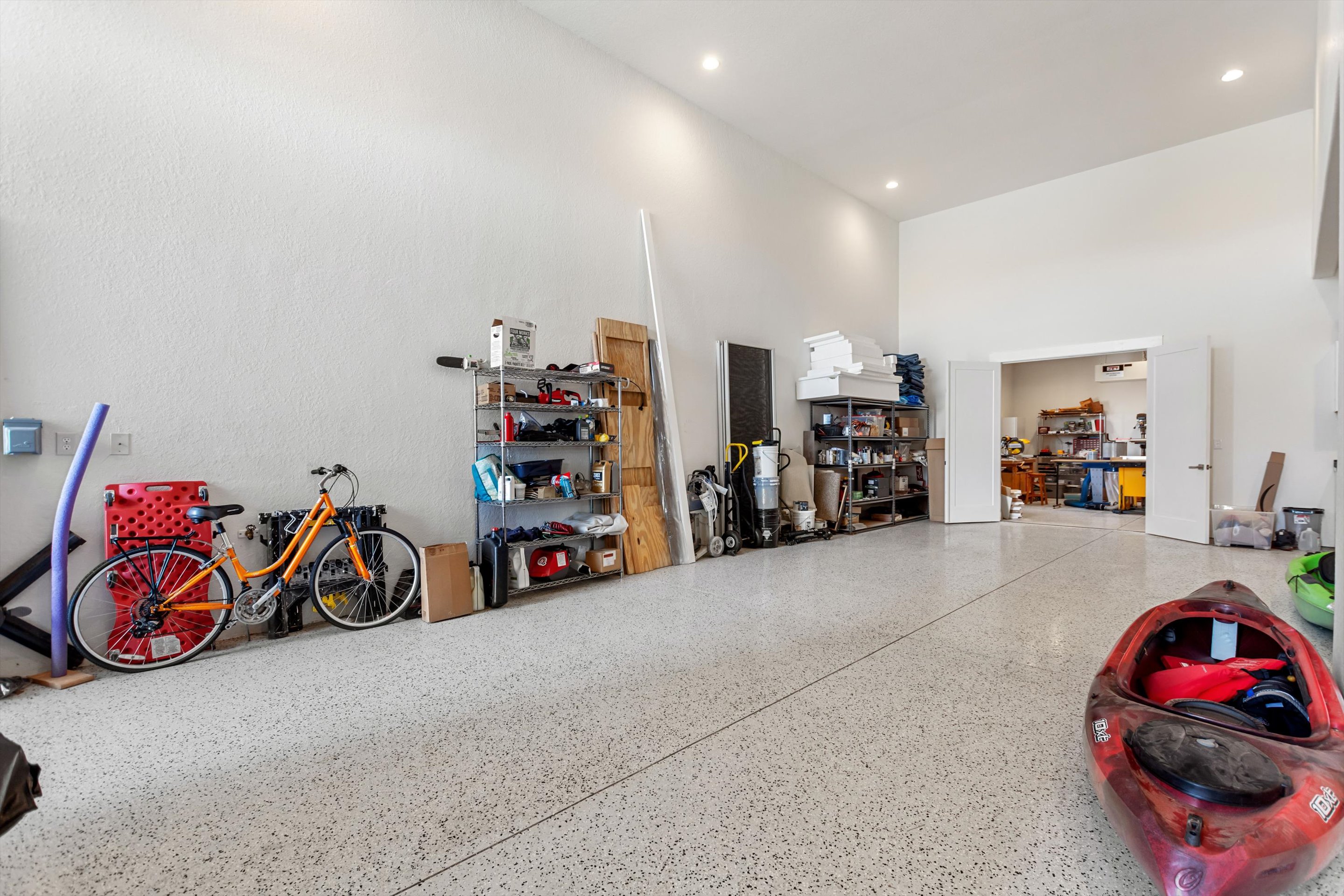 Large bay interior showing epoxy floor, high ceiling and open workshop doorway